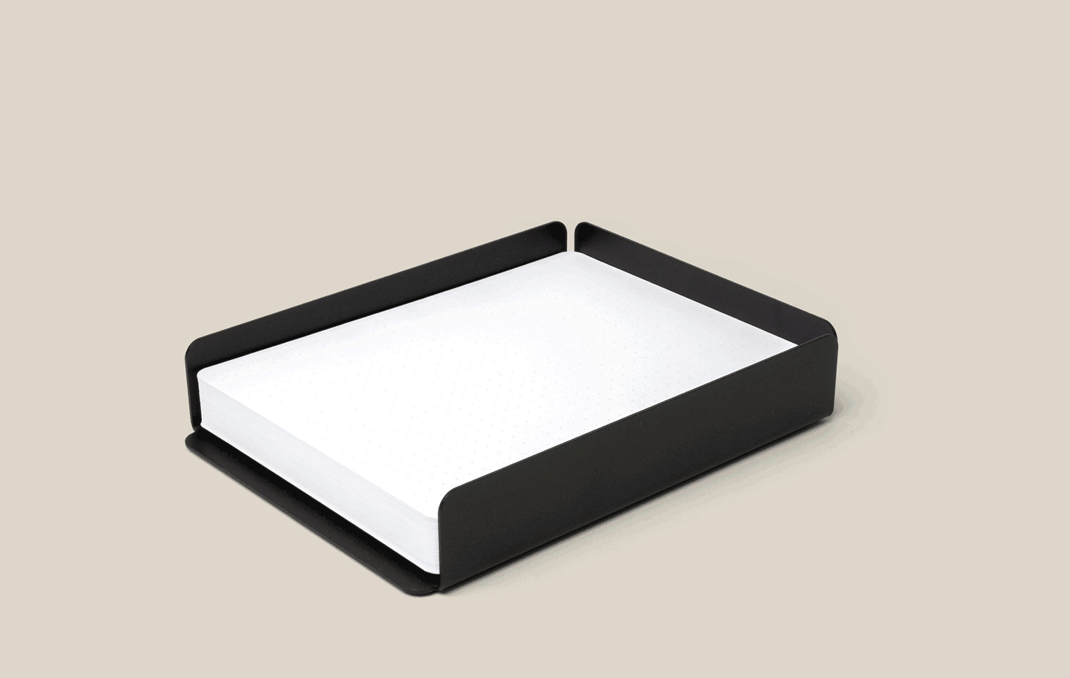 A black metal letter tray holding a stack of white paper, placed on a plain beige background.