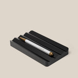 A silver and gold pen with "UGMONK" engraved rests in the Analog Multi Pen Tray (Black Aluminum) on a light beige background.