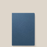 A closed Layflat Notebook (Navy) with an embossed geometric diamond cover and Smyth sewn binding is shown on a plain light beige background.