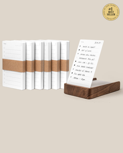 The Analog Daily Focus Kit + 6 Refills (Walnut) is shown with white notepads, brown paper bands, and a walnut card holder displaying a handwritten to-do list. A #1 Best Seller badge appears in the top right corner.