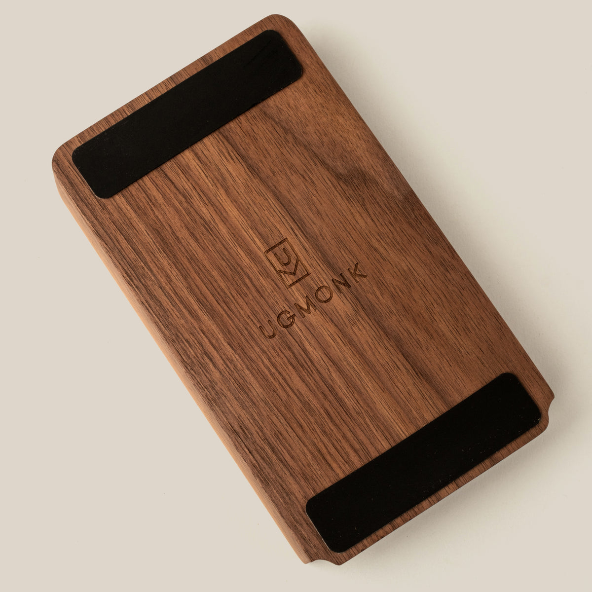 A rectangular walnut Analog Annual Kit with two black strips at the top and bottom, engraved with the Ugmonk logo and name in the center, photographed on a light beige background.