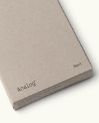 A minimalist, light brown cardboard box labeled "Analog" and "Next" in small black letters on the corners, designed for Analog - Next Cards (1-Pack). Ideal for organizing dot grid cards or goal-setting tools.
