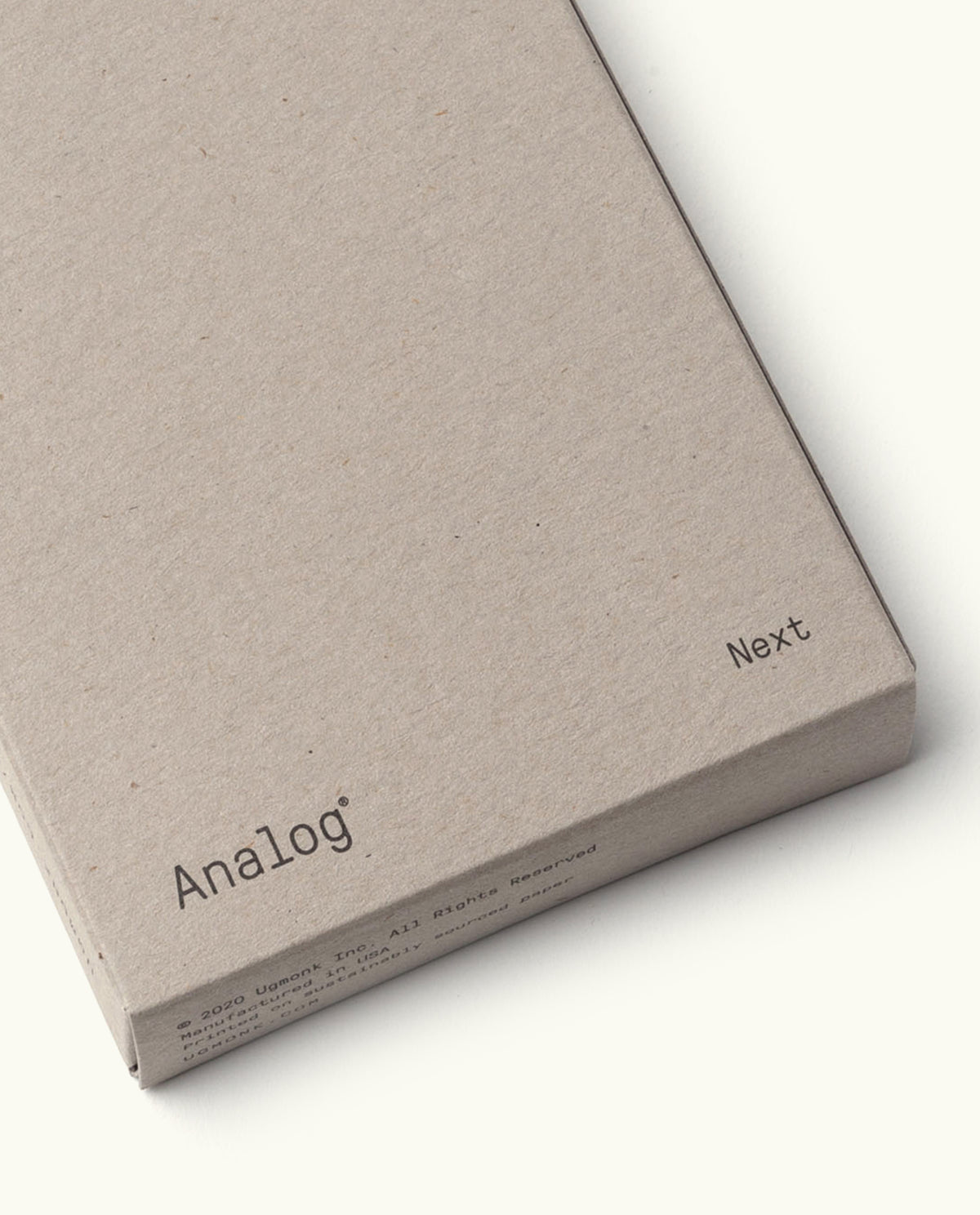A minimalist, light brown cardboard box labeled "Analog" and "Next" in small black letters on the corners, designed for Analog - Next Cards (1-Pack). Ideal for organizing dot grid cards or goal-setting tools.