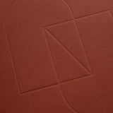Embossed geometric shapes—a rectangle, triangle, and two semicircles—are outlined on the textured cover of the maroon Layflat Notebook.