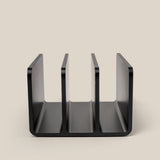 A black, three-slot desktop organizer from The Complete Analog Collection (Black Aluminum) stands upright on a beige surface, photographed from the front to display its U-shaped, open compartments.