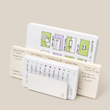 Three open notebooks stand upright. The back features colorful floor plans; the middle, handwritten notes and a meal plan. In front, a small calendar peeks from its cover next to the Analog Card Organizer (Silver Aluminum) for sleek card storage.