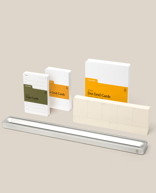 A set of stationery items from the Analog Card Bar – Pro Kit (Silver), featuring Task Cards and grid cards in white and green packaging, a long silver Analog Card Bar desk organizer, and a row of small cream-colored cards displayed against a beige background.