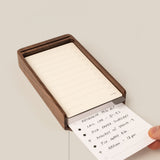 A hand slides a task card under a stack in the Analog Daily Focus Kit (Walnut)—a sleek wood card holder for your daily tasks, such as research, calls, podcasts, repairs, and appointments.