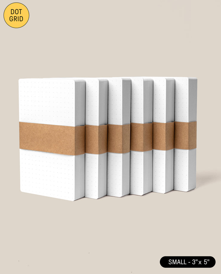 Six Analog Dot Grid Cards - Small (6-Pack) are stacked upright, wrapped with a brown paper band. A yellow “DOT GRID” and black “SMALL – 3 x 5” label appear in the corners—perfect for analog note-taking or as dot grid index cards.
