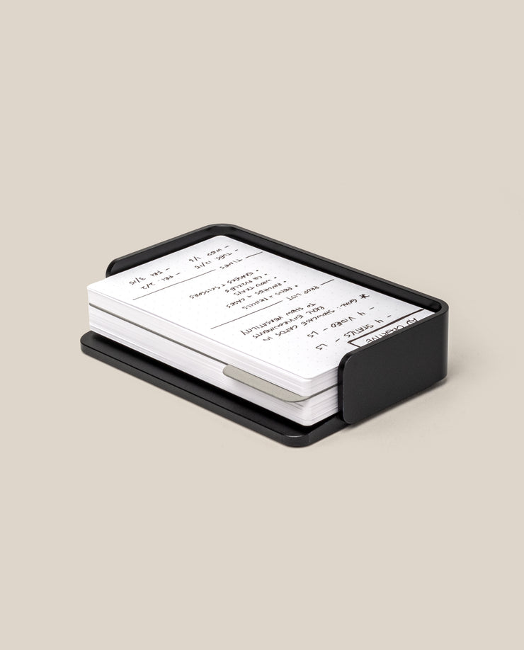 The Complete Analog Collection (Black Aluminum): a black metal organizer holding white index cards with handwritten notes, displayed on a neutral beige background.
