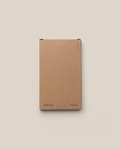 A plain brown cardboard box with “Analog” on the lower left and “Someday” on the lower right holds the Analog - Someday Cards (1-Pack), ideal for storing your planning cards, set against a light beige background.