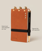Tan Leather Discbound Analog notebook with three metal rings, featuring full-grain leather covers, an elastic closure band, and a black UGMONK-branded pen in the pen loop. Includes 3 refills. Note: Pen sold separately; compatible with Analog Task Cards.