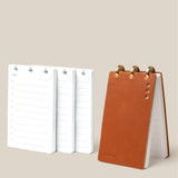 Small open planner with white pages and a brown leather cover on a beige background