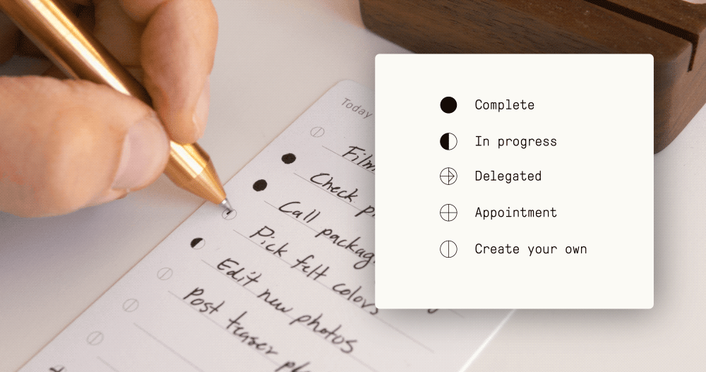 A hand writes on a to-do list with a gold pen. Next to it is a key: solid circle for complete, half-filled for in progress, arrow for delegated, circle for appointment, and plus for create your own.