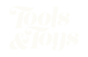 Faded, stylized text reading Tools & Toys in a decorative font on a light gray background.