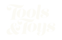 Stylized cream-colored text on a light gray background reads “Tools & Toys” in a bold, decorative font with curls and flourishes.
