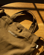 Sturdy olive green Ugmonk Utility Tote (Olive) canvas bag with a snap closure and the word UGMONK printed in white.