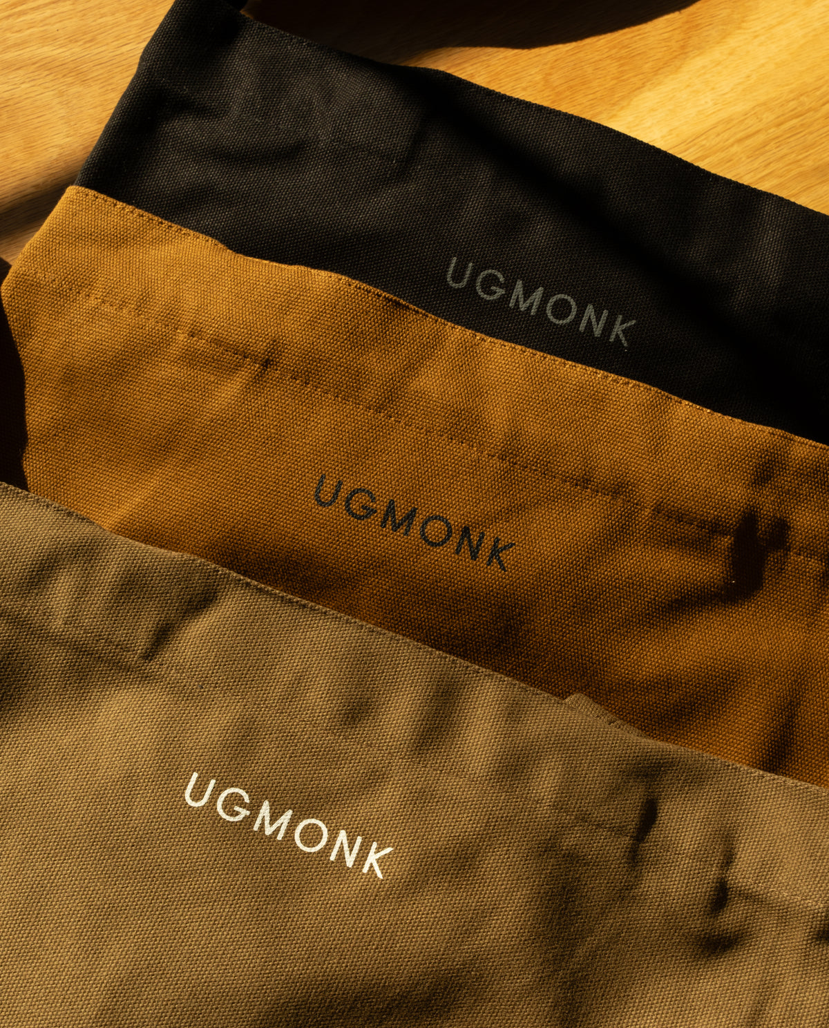 Utility Tote Bundle - Set of 3 featuring three heavyweight cotton tote bags in black, tan, and olive, each with the brand name printed on the front.