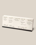 The Analog Weekly Planning Kit (Black Aluminum) is a desktop planner with seven sections for each day, labeled for meal ideas, ingredients, cooking times, and notes. It features a sleek black aluminum base for stylish organization.