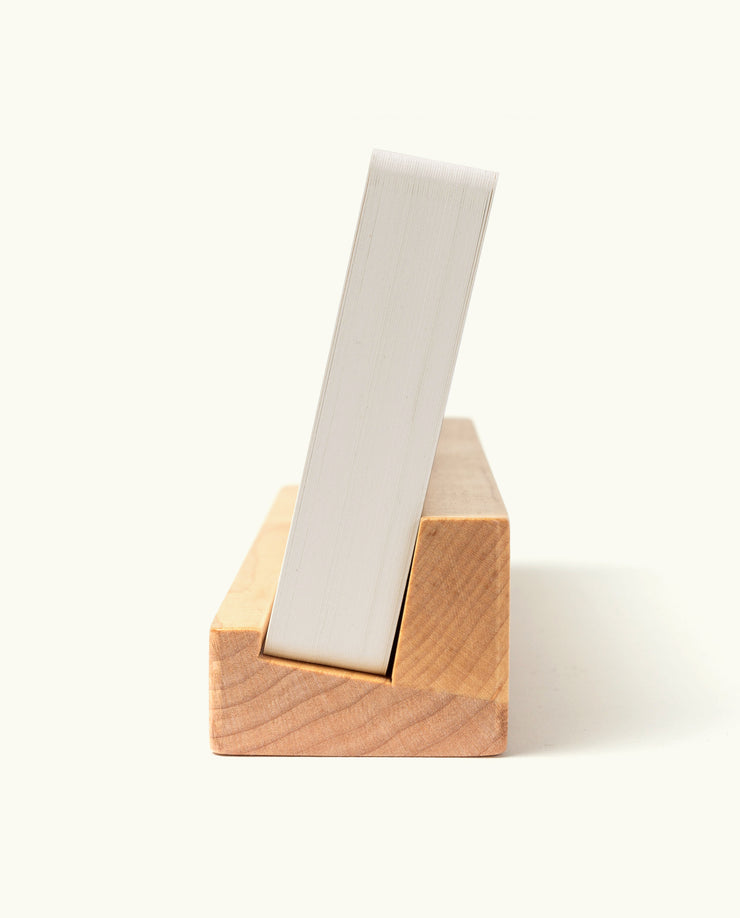 An Analog Weekly Planning Kit (Maple) stands vertically at an angle in a wooden holder, photographed from the side on a plain white background.