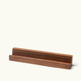 The Analog Weekly Card Holder (Walnut) is handcrafted in Pennsylvania with a groove for displaying Analog Weekly Cards, a tablet, phone, or book—all on a plain light background.