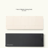 A set of 52 Weekly Cards from the Analog Annual Refill (12 Task Packs + Weekly Cards), featuring beige day-of-week cards atop a black box labeled "Analog Weekly," all displayed on a plain white background.