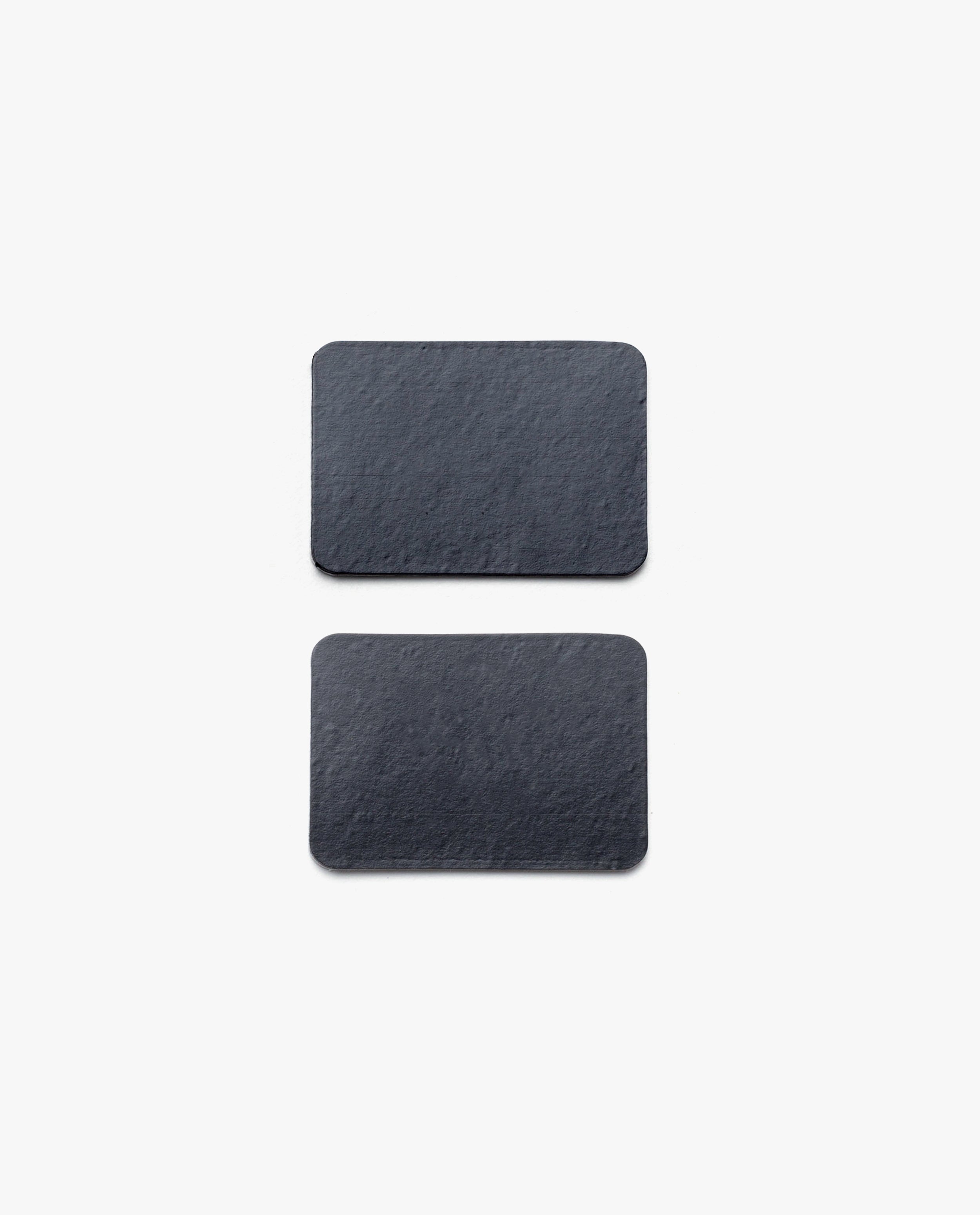 Two rectangular, black slate tiles with rounded corners—part of the Warehouse Item - Magnet Kit (Pen Tray and Analog Weekly)—are placed vertically on a plain white background, one above the other.