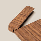 A close-up of The Analog Bundle (Walnut)—a modern, minimalist wooden stapler with a smooth finish—partially open beside a refillable pen on a light beige background.