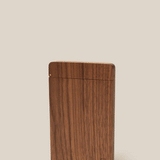 The Analog Bundle (Walnut) is a slim, rectangular walnut card holder with a smooth finish. It stands upright against a plain beige background, featuring a thin horizontal slot near the bottom and a small engraved logo in the corner.