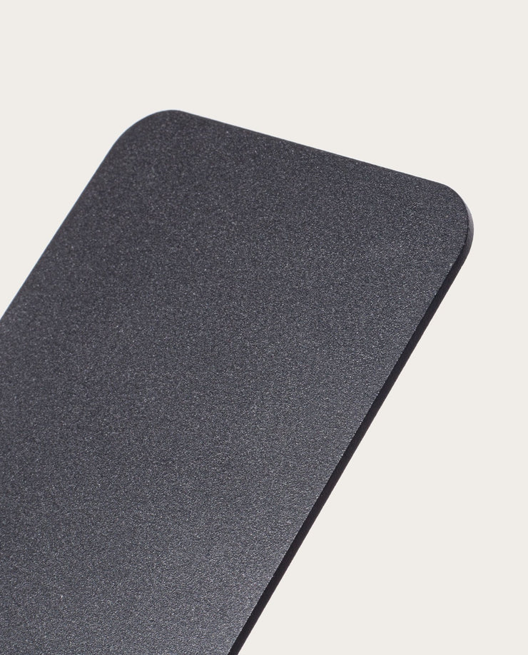 A close-up of the Gather 1x4 Base Plate (Black), a rectangular, matte black steel panel with a textured powder-coated finish and rounded corners, shown against a plain, light background.