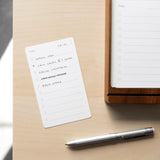 A small notepad with a handwritten to-do list lies on a light wooden desk next to a Craft Design Technology Multifunctional Pen and a larger notepad. The list includes tasks like "Email Josh" and "Call Laura @ 2:30 PM.