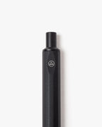 A close-up of the HMM Ballpoint Pen (Black)—a hexagonal, black aluminum pen displaying the HMM logo in a circle near the top—photographed against a white background. This elegantly designed pen features a refillable mechanism for long-lasting use.