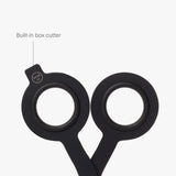 A close-up of HMM Scissors (Black) showcases their round handles, with one handle featuring a labeled built-in box cutter extending from the edge, all set against a white background.