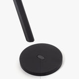 A round, black magnetic metal base is displayed on a white background, with HMM Scissors (Black) hovering above it. A label points to the base, reading "Magnetic base.