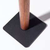 The Gather Headphone Stand (1x1 - Black/Walnut) features a solid walnut cylindrical pole set into a flat, black powder-coated steel square base, creating a minimalist look against a bright white background.