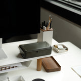 A modern desk features a computer, pen holder, trays with office supplies, and a Toyo Steel Stackable Storage Box T-190 (Military Green) made in Japan, all arranged near a large window that provides natural light.