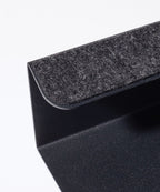 Close-up of the Gather Laptop Stand (Black/Walnut), featuring a black metal frame with a dark gray felt pad, an angular design, and a walnut accent. Made in the USA and set against a plain white background.