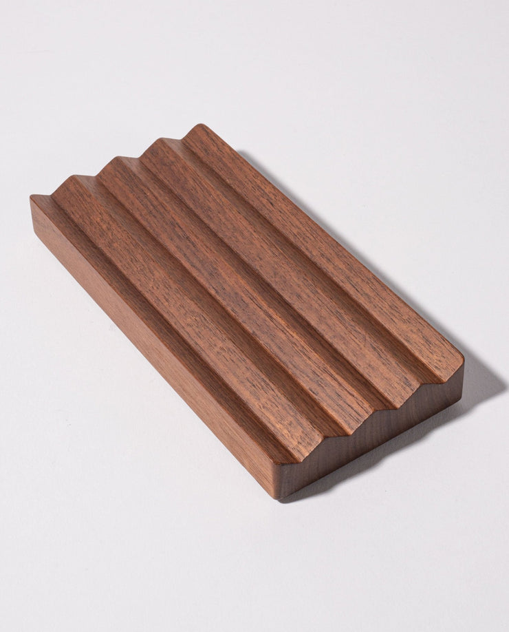 The Gather Wood Zigzag Tray (2x1 - Walnut) is crafted from solid walnut and features a unique zigzag design, making it a stylish holder for pens and pencils.