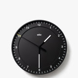 The Braun Wall Clock (Black) features white hour and minute hands, a slim yellow second hand, and silent operation. Clear white tick marks and numbers on a plain white background make the clock easy to read, displaying 10:30:50.