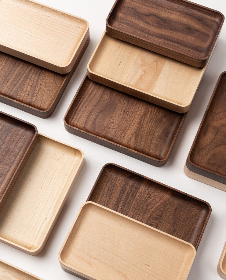 Several Valet Tray (Maple - Medium) pieces are arranged in a grid on a white surface, highlighting their smooth finishes, visible natural wood grain, and expert handcrafted quality.