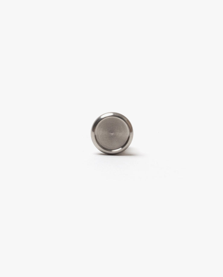 A small, round, silver-colored button battery rests on a white background, evoking the sleek closures featured on the Discbound Heirloom Journal Bundle (Black Leather - Standard 6" x 8.5" + 3 Refills).