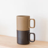 A Hasami Porcelain Mug (Matte Black) sits atop a light wooden shelf against a plain white background, highlighting the timeless elegance of Japanese craftsmanship.