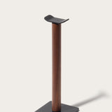 The Gather Headphone Stand (1x1 - Black/Walnut) features a solid walnut vertical column, a black powder coated steel base, and a curved top to hold headphones, all set against a plain light background.