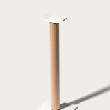 The Gather Headphone Stand (1x1 - White/Maple) features a tall maple wood post, a square white base, and a curved white top platform, all set against a simple light background for a minimalist look.