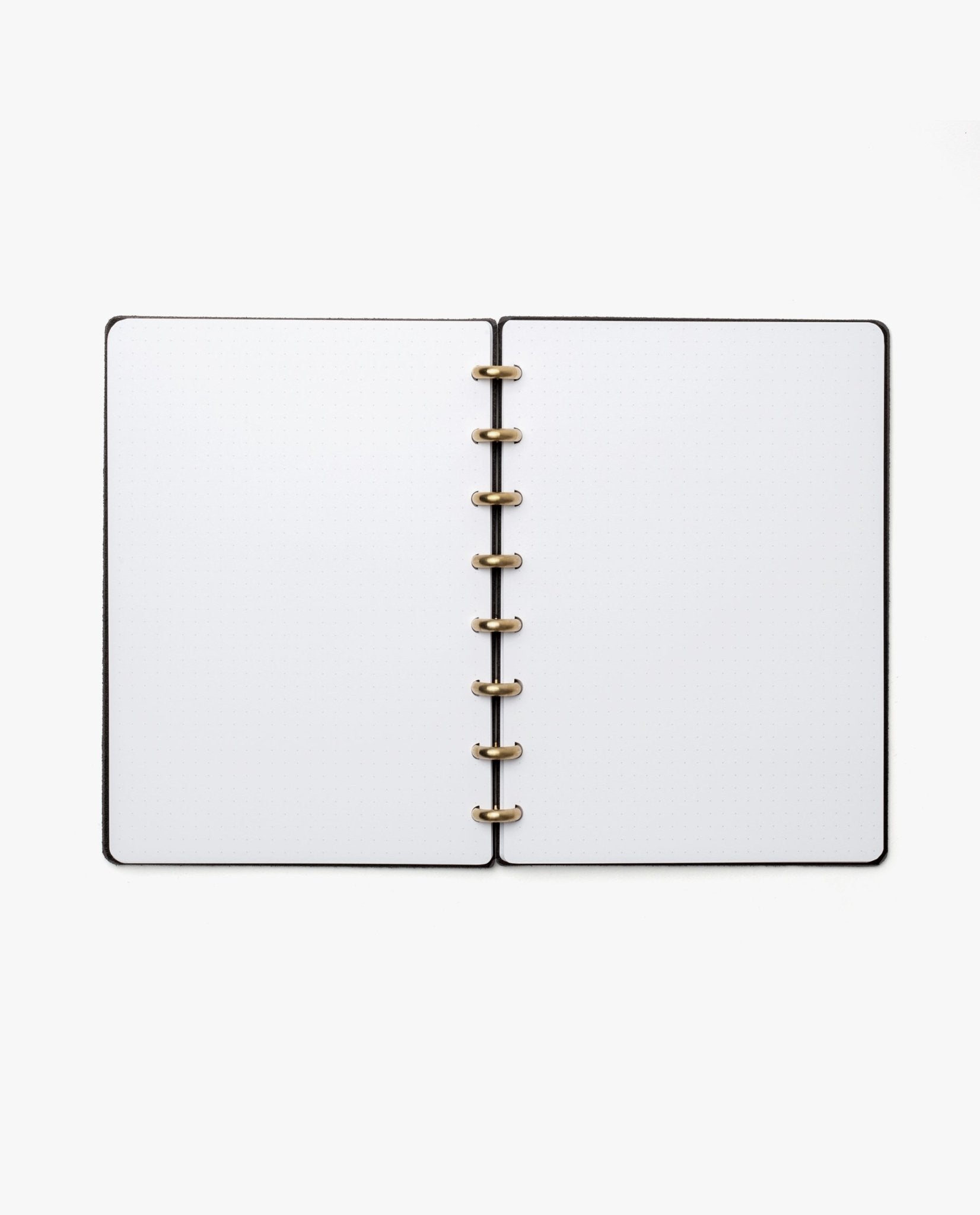 The Discbound Heirloom Journal Bundle (Black Leather - Standard 6" x 8.5" + 3 Refills) is open to blank white pages, showcasing its gold-colored ring binding, viewed from above on a white background.