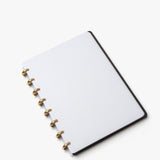 The Discbound Heirloom Journal (Black Leather - Standard 6" x 8.5") features refillable dotted white pages and gold rings, displayed open on a white background.