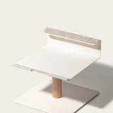 The Gather Laptop Stand (White/Maple) features a minimalist, square base and light wood central post, topped with a white square platform accented by felt padding for comfort; crafted in the USA.