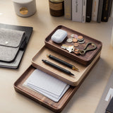 The Valet Tray (Walnut - Small), handcrafted in Pennsylvania, neatly holds coins, keys, a keychain, earbuds, two pens, and note cards on a tidy desk alongside books, a notebook, and a coffee cup.