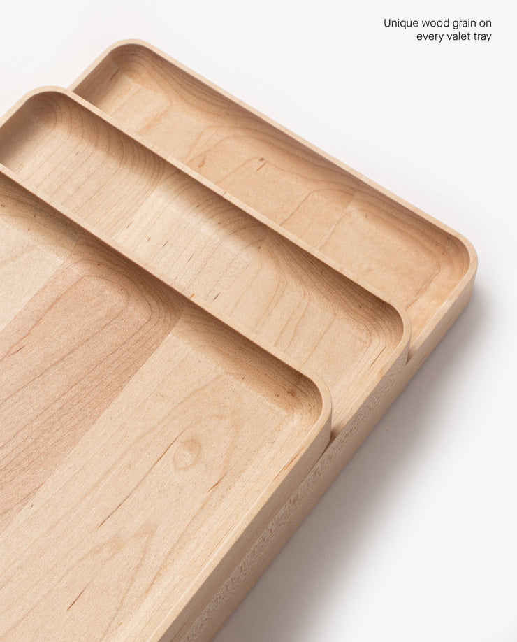 A handcrafted rectangular Valet Tray (Maple - Medium) sits on a white background, displaying unique natural wood grain. Text in the top right corner reads, Unique wood grain on every valet tray.