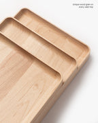 Handcrafted from solid maple, the Valet Tray (Maple – Large) features rounded corners and distinct light wood grain patterns. Text in the upper right corner reads, Unique wood grain on every valet tray.